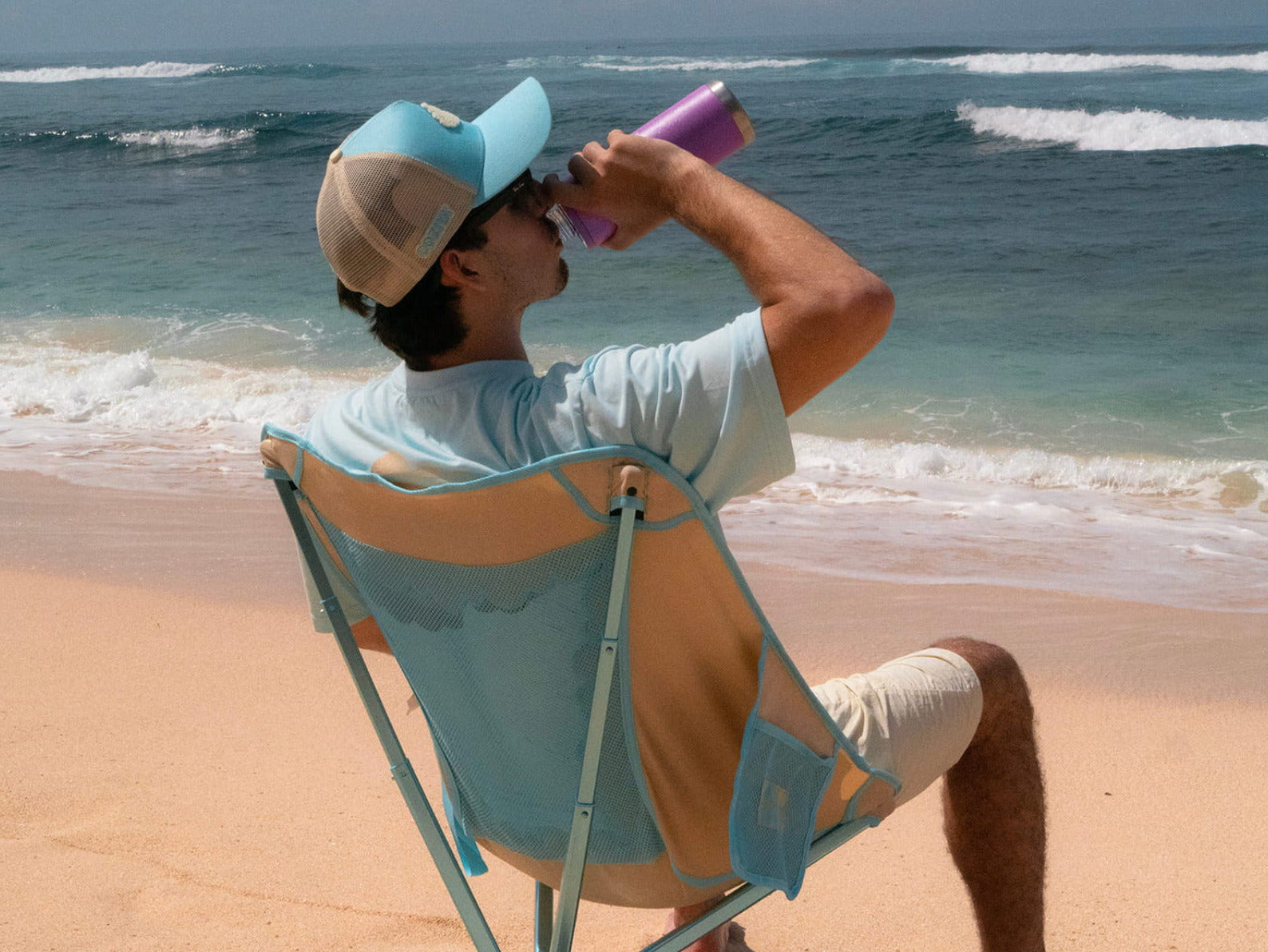 Personne assise sur la Cloud Chair™ Coziya® à la plage avec gourde Hook650™ – lifestyle outdoor